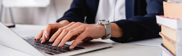 Cropped view of interpreter typing on laptop near dictionaries on blurred foreground, banner — Stock Photo