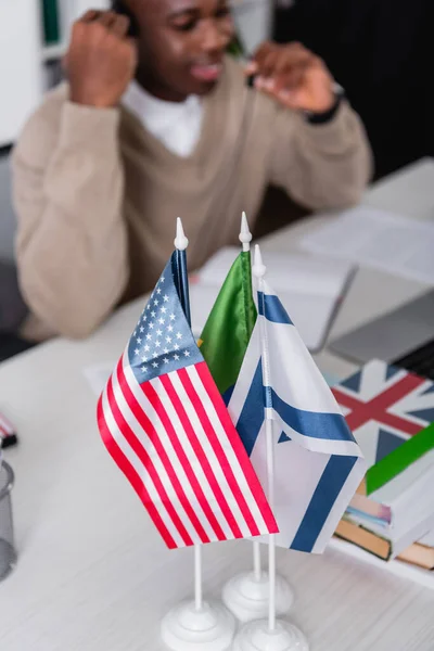 Foyer sélectif des drapeaux américains et israéliens près des dictionnaires et traducteur afro-américain sur fond flou — Photo de stock