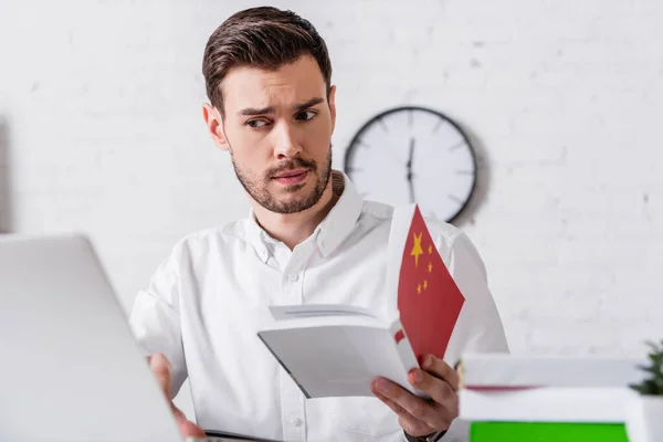 Nachdenkliche Dolmetscherin mit chinesischem Wörterbuch während ihrer Arbeit im Übersetzungsbüro, verschwommener Vordergrund — Stockfoto