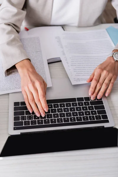 Visão parcial do tradutor digitando no laptop perto de documentos no escritório — Fotografia de Stock