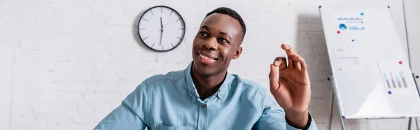 Hombre de negocios africano feliz mostrando gesto bien en la oficina, bandera - foto de stock