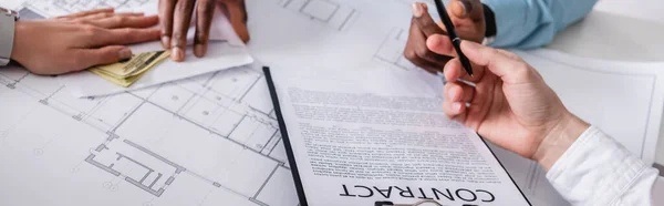 Visão parcial de parceiros de negócios dando dólares em envelope, contrato e caneta para empresário afro-americano, banner — Fotografia de Stock