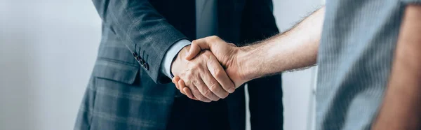 Vista recortada del inversor y hombre de negocios estrechando la mano en la oficina, pancarta - foto de stock