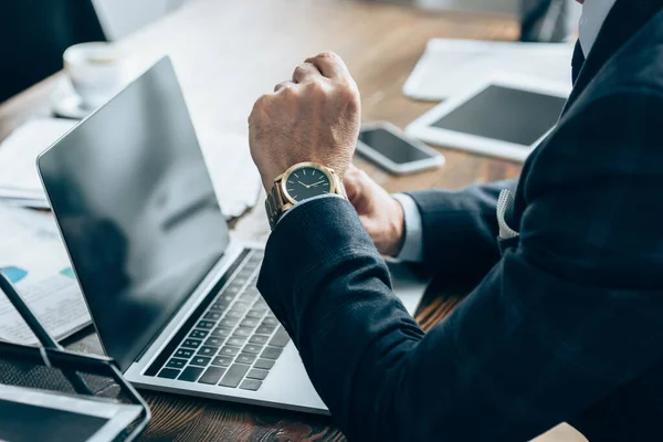 Vue recadrée de l'homme d'affaires assis près des appareils avec écran vierge et papiers dans le bureau — Photo de stock