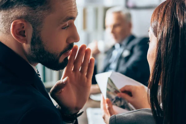 Geschäftsmann spricht mit Kollege, der Geld und Umschlag in der Hand hält, und Berater auf verschwommenem Hintergrund — Stockfoto