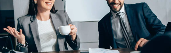 Vista recortada de los empresarios sonrientes con café en la oficina, pancarta - foto de stock