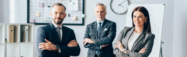 Fröhliche Geschäftsleute, die im Büro mit verschränkten Armen in die Kamera blicken, Banner — Stockfoto