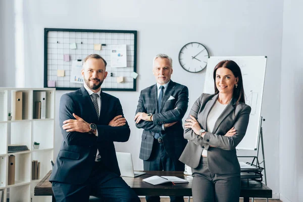 Positive Geschäftsleute lächeln in die Kamera neben reiferen Kollegen im Amt — Stockfoto