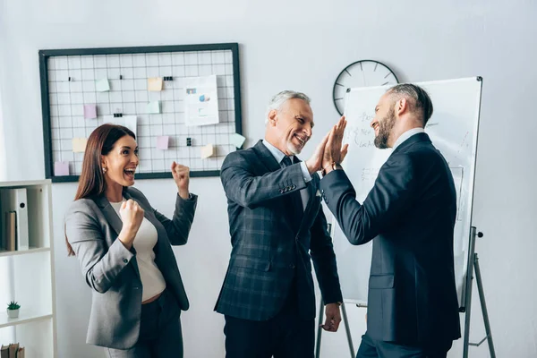 Smiling businessman giving high five near cheerful businesswoman in office — Stock Photo