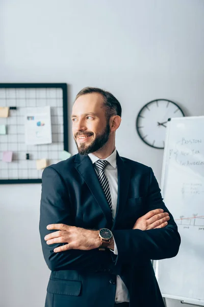 Homme d'affaires souriant avec les bras croisés regardant loin dans le bureau — Photo de stock