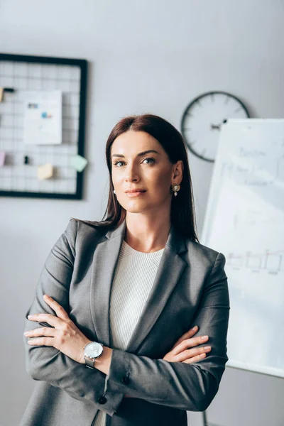 Mujer de negocios con brazos cruzados mirando a la cámara en la oficina - foto de stock