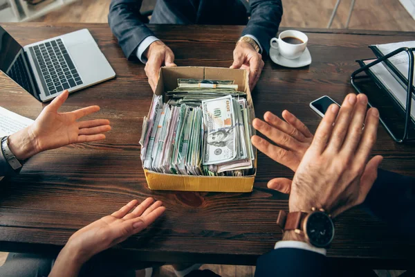 Vista recortada de la caja de espera del hombre de negocios con dinero en efectivo cerca de colegas que muestran el gesto de stop en primer plano borroso - foto de stock