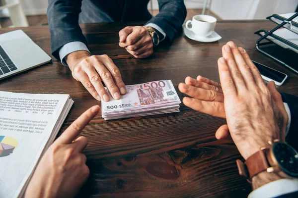 Cropped view of business people showing stop gesture and pointing at euro banknotes near colleague and papers on blurred foreground — Stock Photo