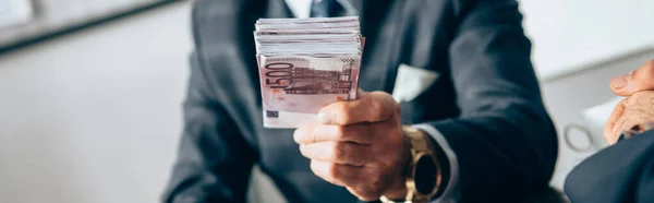 Vista ritagliata dell'investitore che detiene banconote in euro presso un uomo d'affari in primo piano sfocato, banner — Foto stock