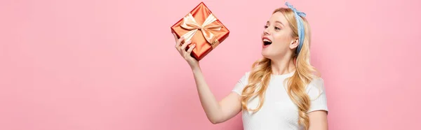 Happy blonde young pregnant woman with gift box on pink background, banner — Stock Photo