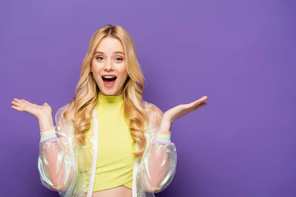 Feliz rubia joven en traje colorido sobre fondo púrpura - foto de stock