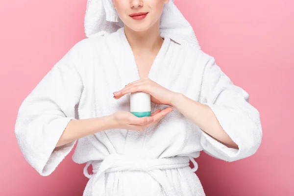 Cropped view of young woman in bathrobe holding deodorant on pink — Stock Photo