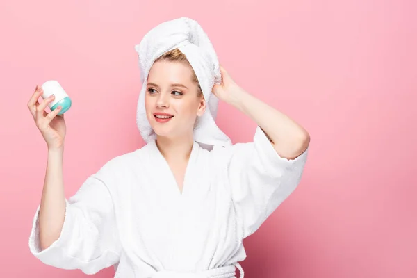 Junge Frau im Bademantel mit Handtuch auf dem Kopf hält Deo auf rosa — Stockfoto