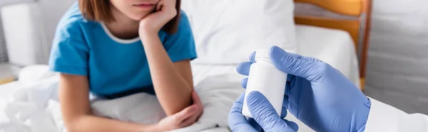 Abgeschnittene Ansicht des Kinderarztes, der Behälter mit Medikamenten in der Nähe des kranken Mädchens in der Klinik aufbewahrt, verschwommener Hintergrund, Banner — Stockfoto