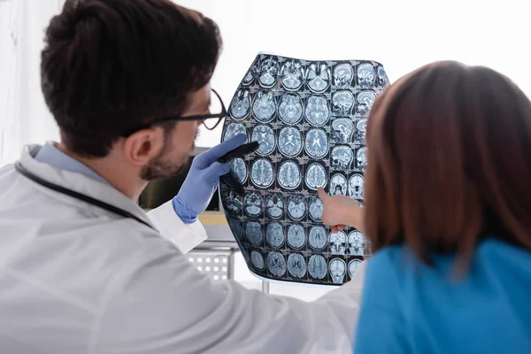 Vista posteriore della ragazza che punta ai raggi X vicino al medico in ospedale — Foto stock