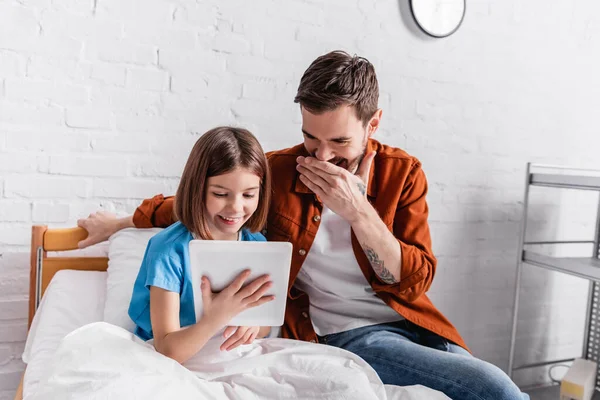 Laughing girl with father using digital tablet in hospital — Stock Photo