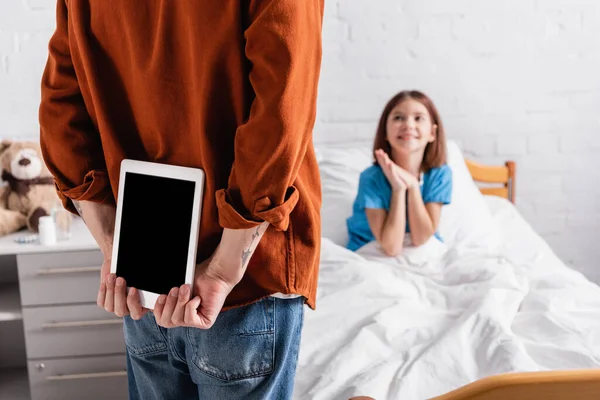 Back view of man holding digital tablet with blank screen near excited girl in hospital, blurred background - foto de stock