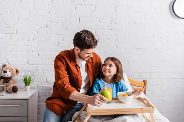 Feliz hombre mirando sonriente hija durante el desayuno en el hospital - foto de stock