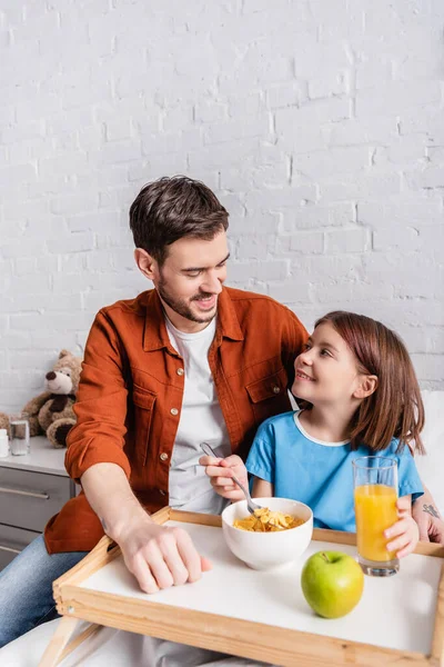 Cheerful dad and daughter looking at each other during breakfast in hospital — Stock Photo
