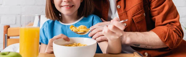 Abgeschnittene Ansicht des Vaters, der Tochter mit Cornflakes füttert, im Krankenhaus, Banner — Stockfoto