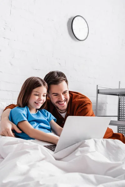 Padre y la hija feliz usando el ordenador portátil en el hospital - foto de stock