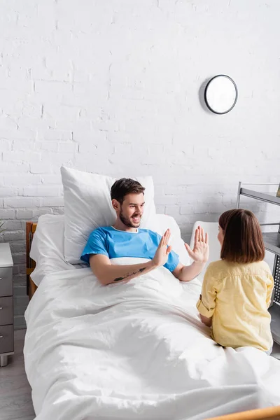 Cheerful man playing patty-cake game with daughter in hospital — Stock Photo