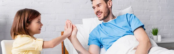 Happy man giving high five to daughter while lying in bed, banner — Stock Photo