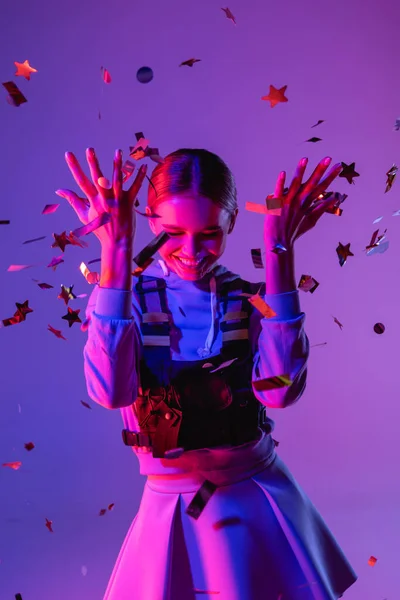 Mulher feliz em roupa elegante jogando confete no roxo — Fotografia de Stock