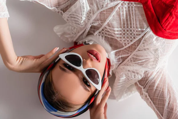 Draufsicht einer trendigen Frau mit Sonnenbrille und Kopftuch, die in die Kamera auf Weiß blickt — Stockfoto