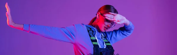 Modelo joven en gafas de sol cubriendo la cara y posando aislado en púrpura, pancarta — Stock Photo