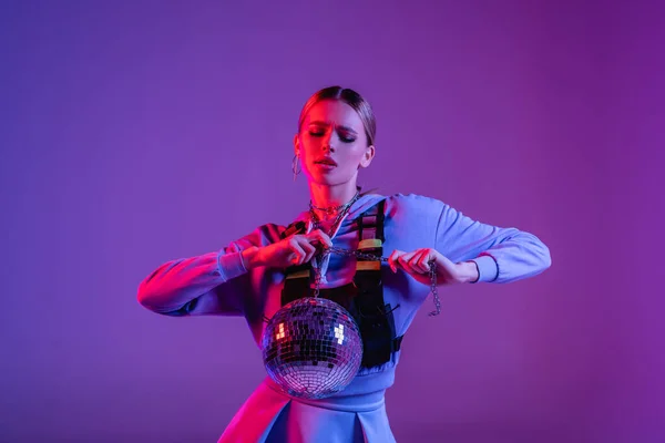 Giovane ed elegante donna in posa con lucida palla da discoteca viola — Foto stock