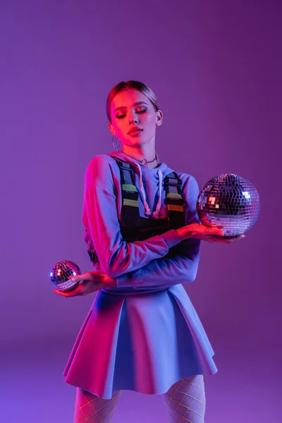 Стильная женщина в юбке с шарами диско на фиолетовом фоне — стоковое фото