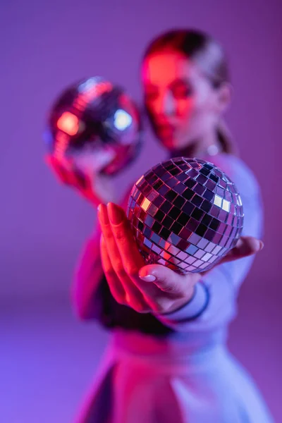 Блискучий диско-куля в руці модної жінки на фіолетовому і розмитому фоні — стокове фото