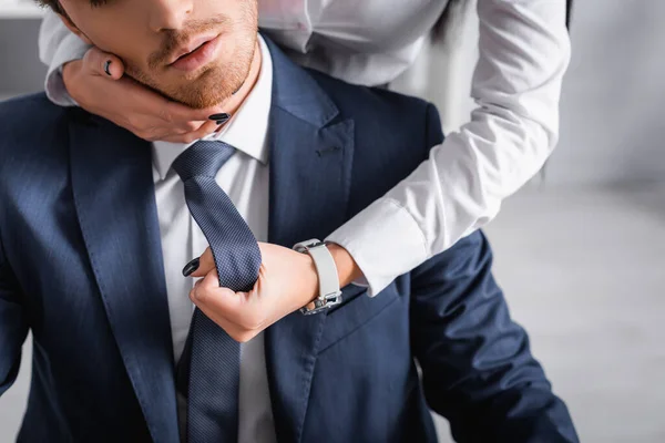 Partial view of secretary flirting with businessman and touching his face in office — Stock Photo