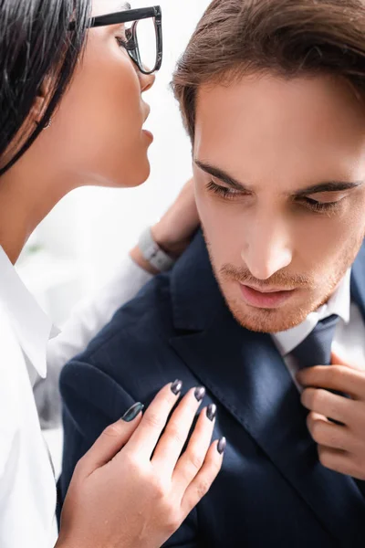 Passionate businesswoman whispering in ear of colleague while flirting in office — Stock Photo