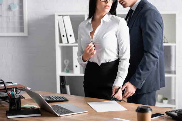 Cropped view of businessman seducing sensual secretary standing with pen at workplace — Stock Photo