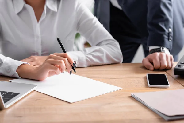 Partial view of businessman near secretary holding pen at workplace — Stock Photo