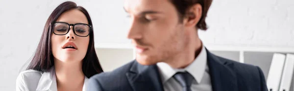 Passionate brunette secretary in eyeglasses near young businessman on blurred foreground, banner — Stock Photo