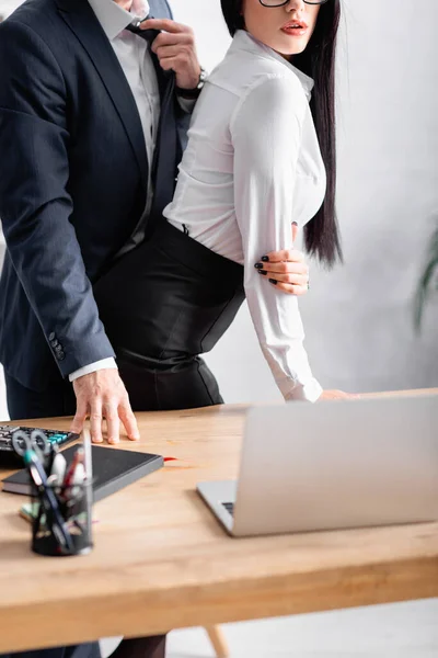 Vue recadrée du secrétaire flirtant avec l'homme d'affaires près du lieu de travail dans le bureau — Photo de stock