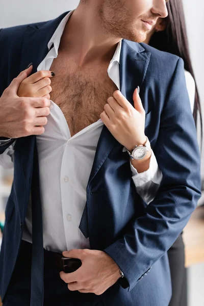 Partial view of seductive secretary unbuttoning shirt of businessman in office — Stock Photo