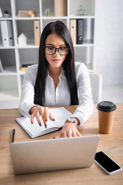 Seductive brunette businesswoman typing on laptop in office — Stock Photo