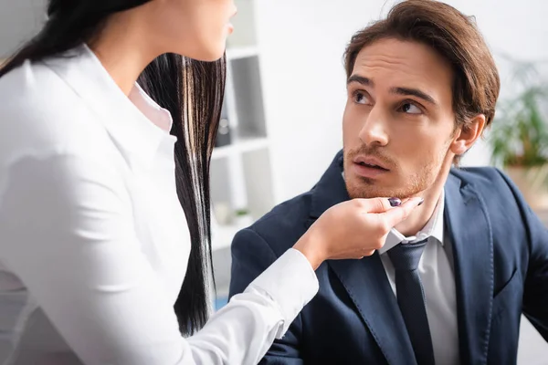 Seductive businesswoman touching chin of young colleague in office — Stock Photo