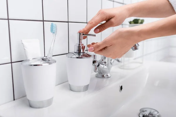 Vista recortada de la mujer usando dispensador de jabón en el baño - foto de stock