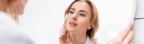 Mujer mirando el espejo y tocando la cara en el baño, pancarta — Stock Photo