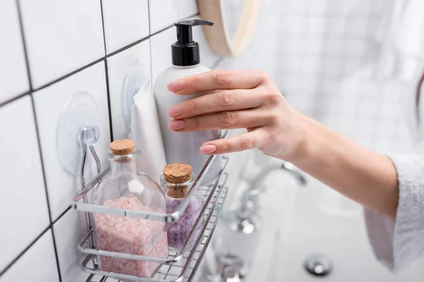 Vue recadrée de la femme prenant bouteille avec lotion corporelle dans la salle de bain — Photo de stock